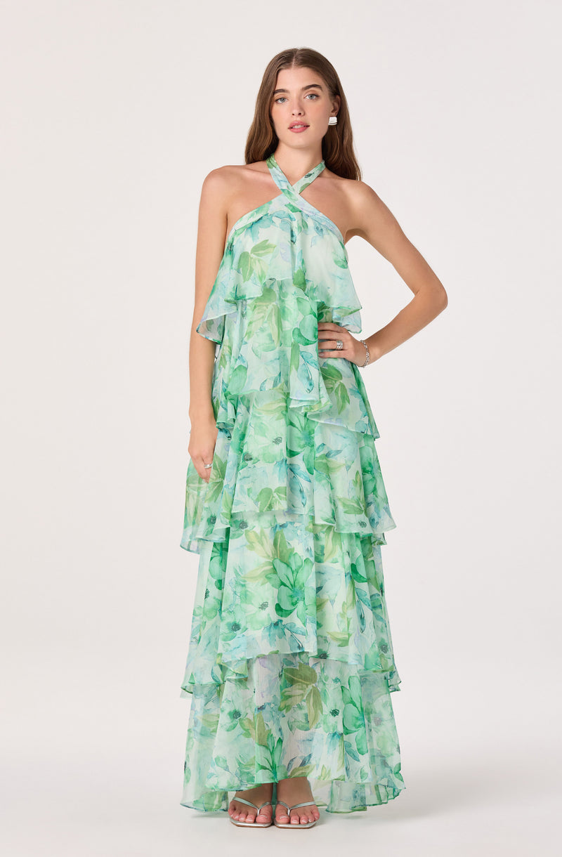 Woman wearing a sleeveless, halter-neck, green floral layered maxi dress.