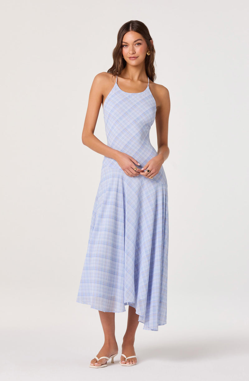 Woman wearing a light blue plaid sleeveless dress with spaghetti straps, flowing midi length.