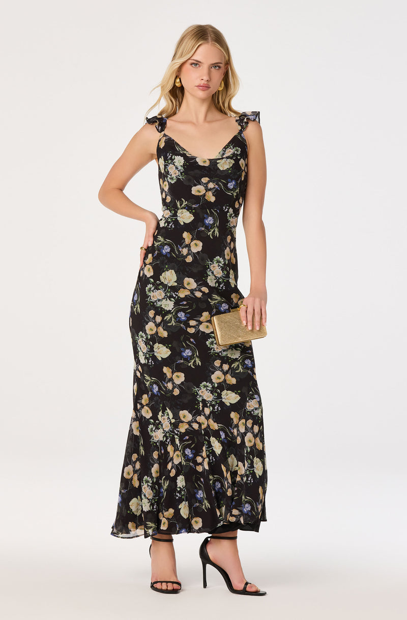 Black floral maxi dress with ruffled shoulder straps, paired with black high heels.