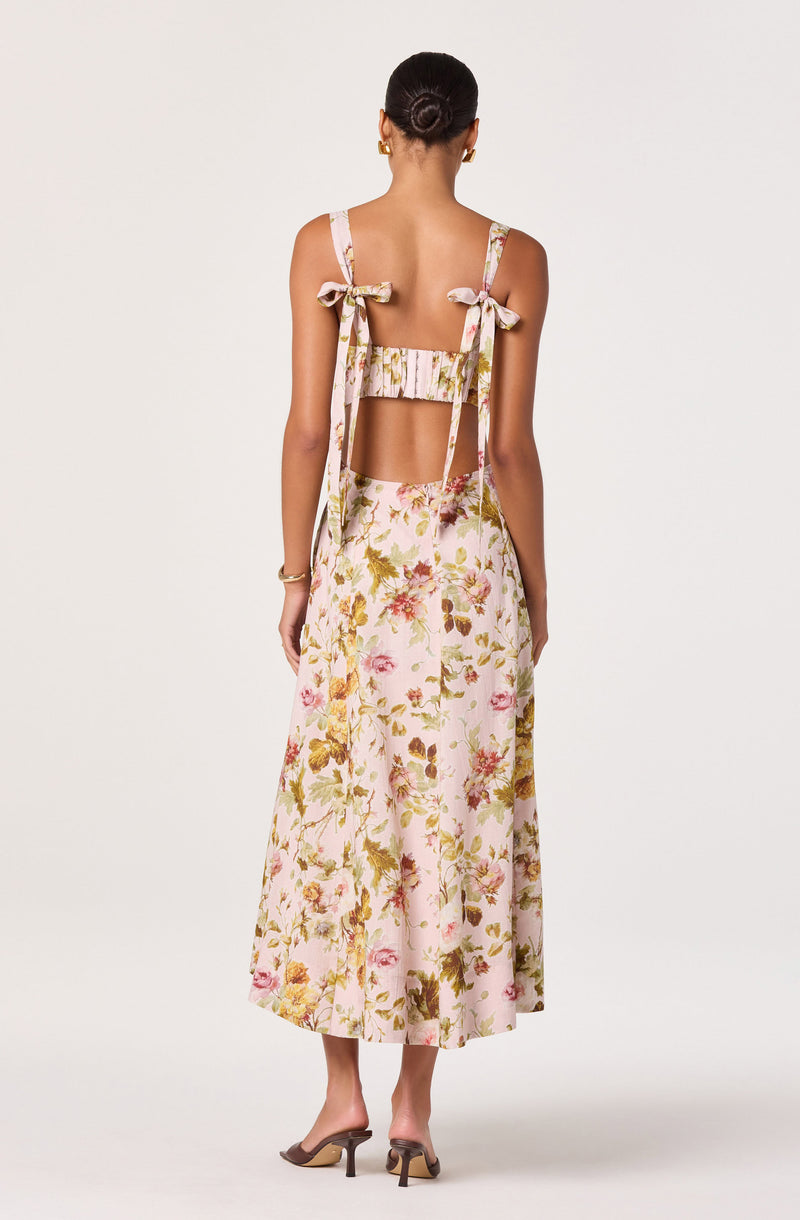 Back view of a woman wearing a sleeveless, floral-patterned crop top with tied shoulder straps and a matching long skirt.