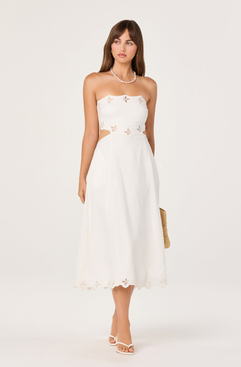 Woman wearing a white strapless dress with gold embellishments on a white background