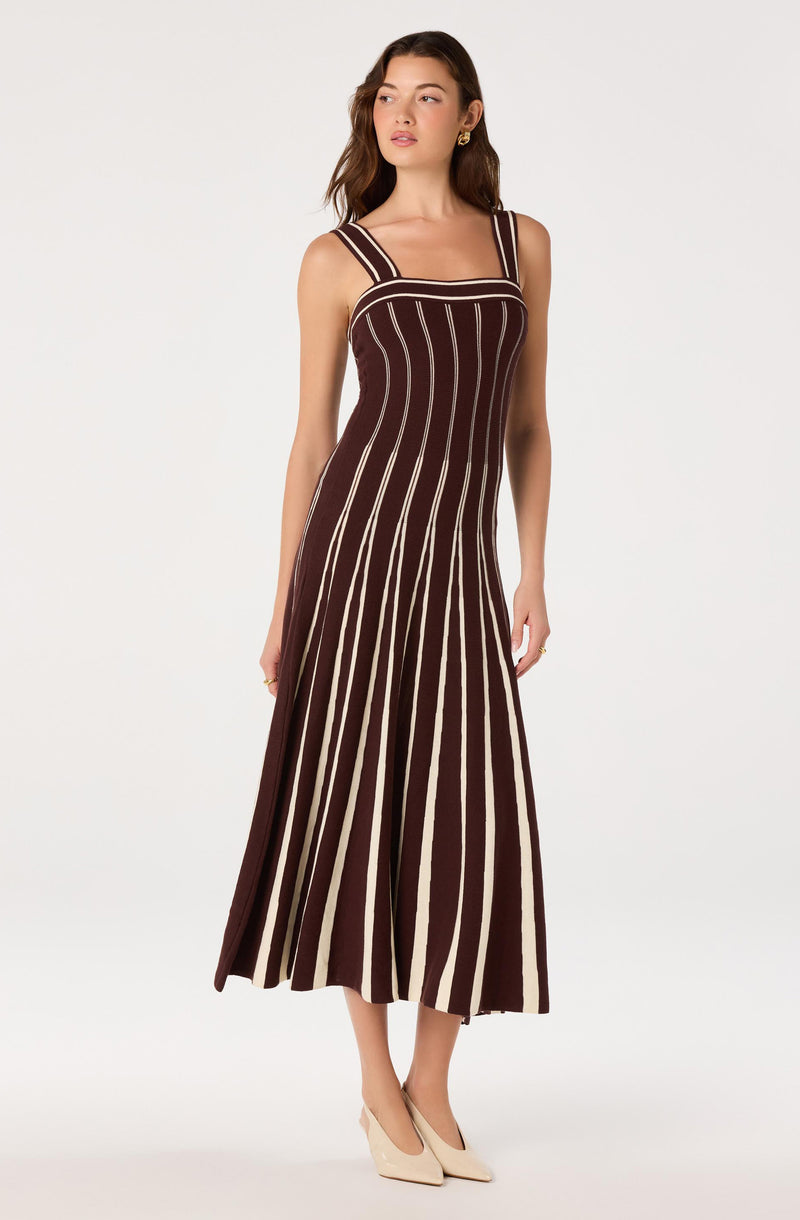 Woman wearing a sleeveless brown dress with vertical beige and white stripes.