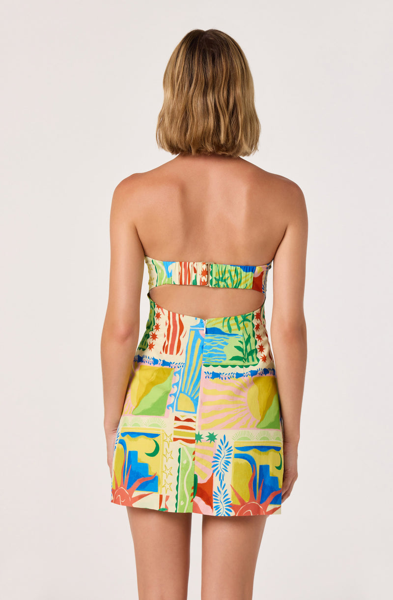 Back view of a woman wearing a colorful, strapless dress with geometric and floral patterns, featuring cut-outs.