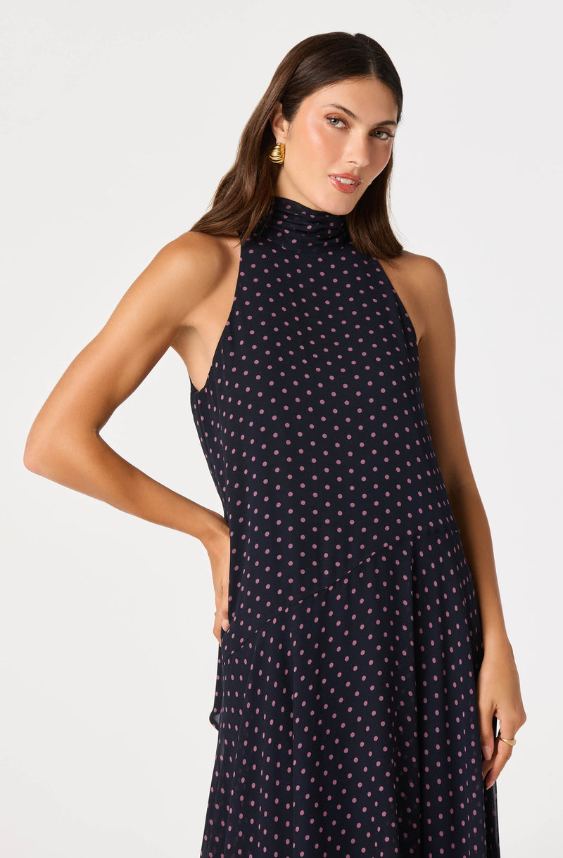 Sleeveless navy dress with pink polka dots and a high neckline.