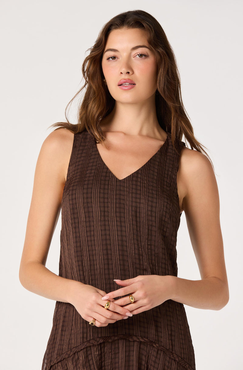Woman wearing a sleeveless brown striped top with a V-neck.
