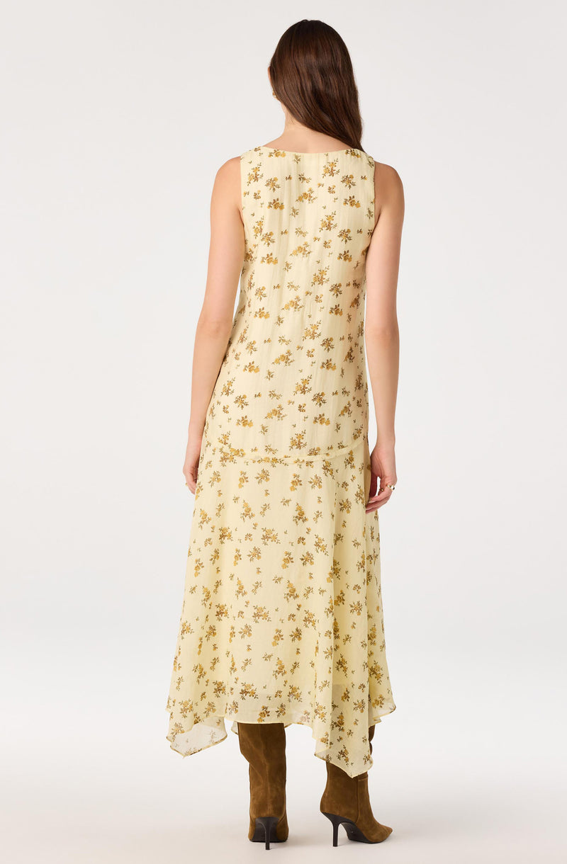 Cream dress with gold floral pattern, sleeveless, ankle-length, worn with brown knee-high boots.
