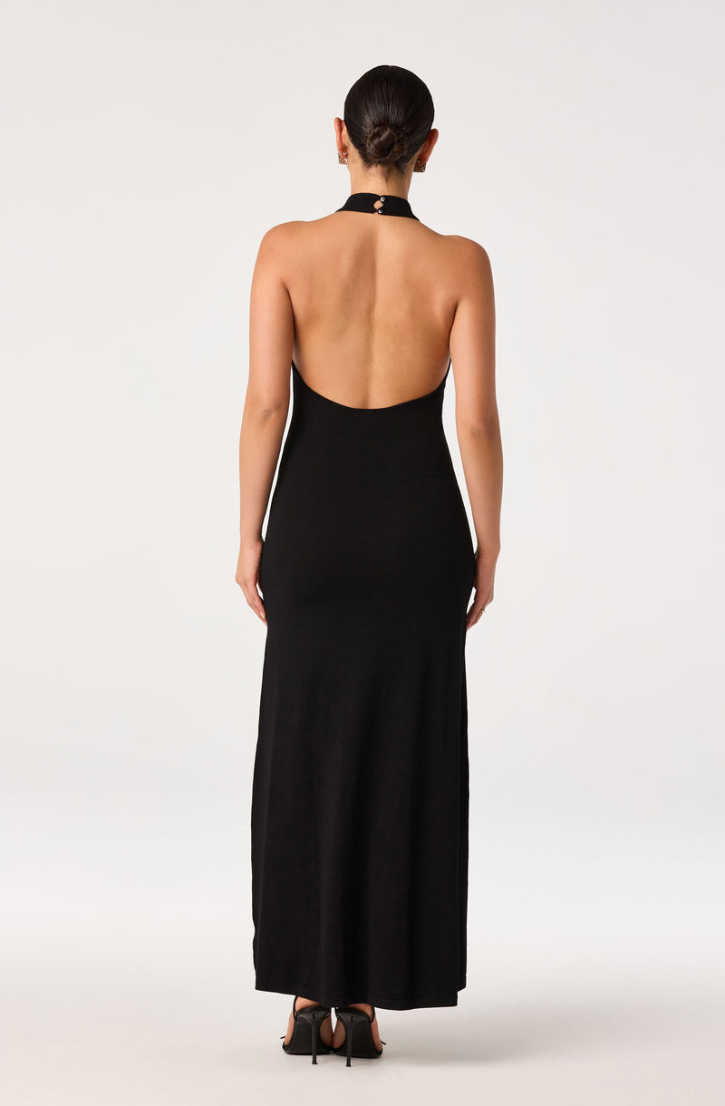 Back view of a woman wearing a long, black, halter-neck gown with open back and high heels.