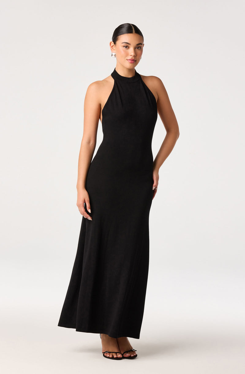 Woman wearing a sleeveless, high-neck, floor-length black gown.