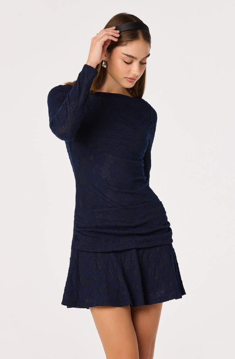 Woman in navy lace dress with long sleeves and ruffled skirt, wearing a black headband.