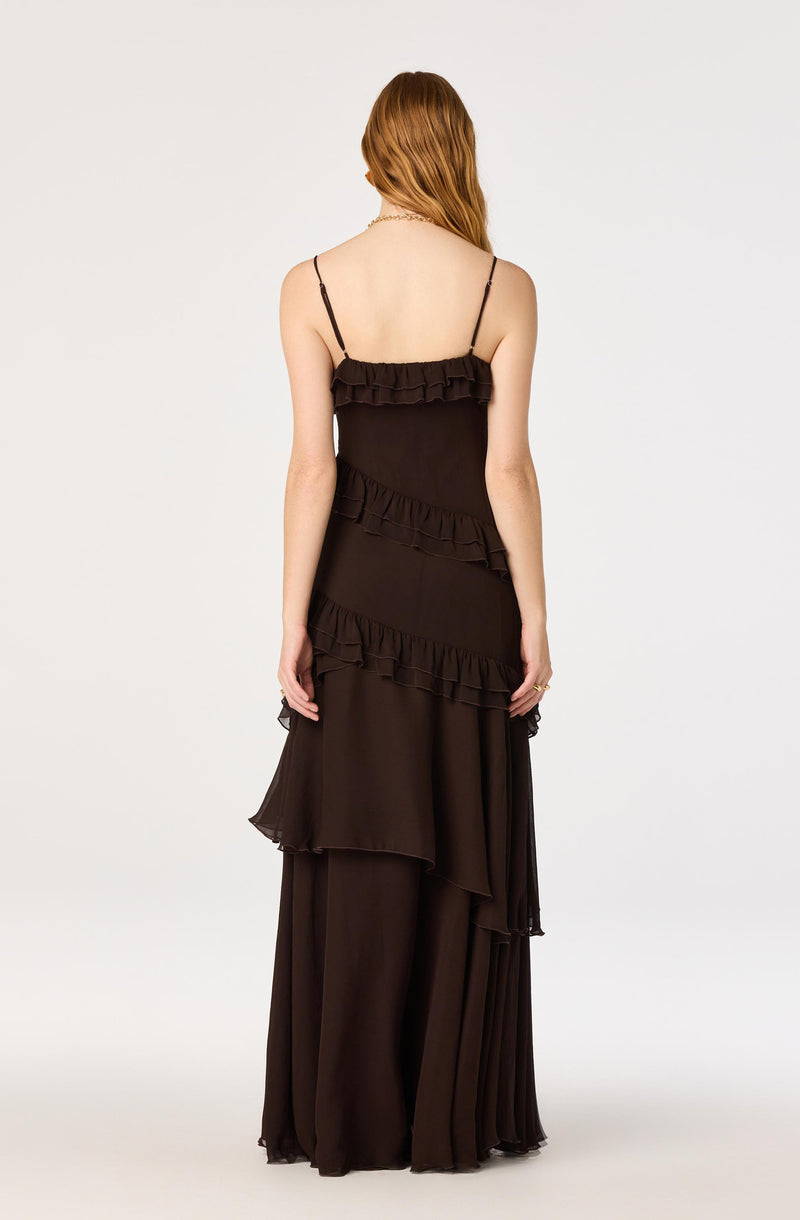 Woman wearing a black spaghetti strap dress with ruffles and layered fabric.