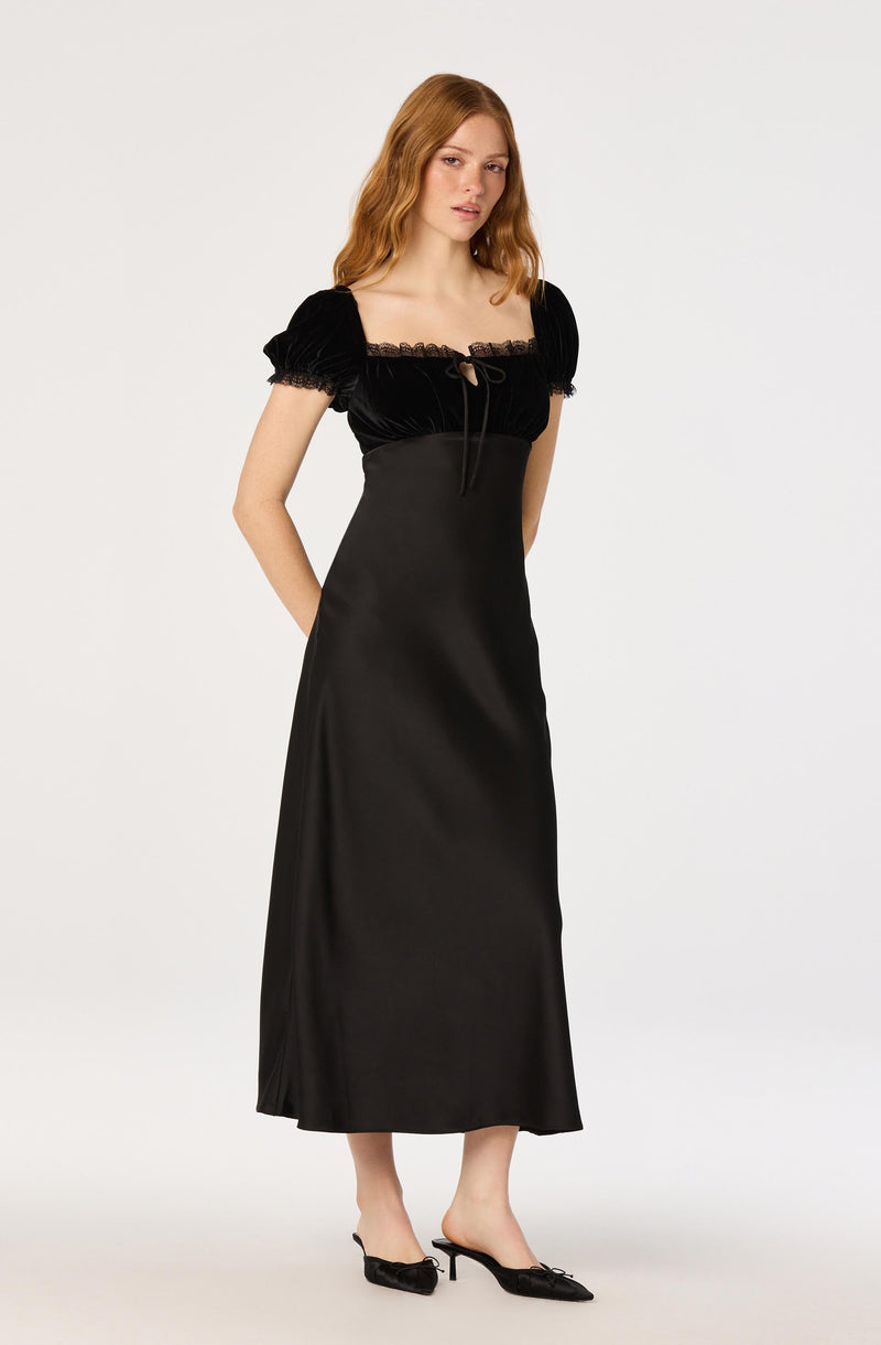 Woman wearing a black dress with puffed sleeves and a lace-trimmed bodice.