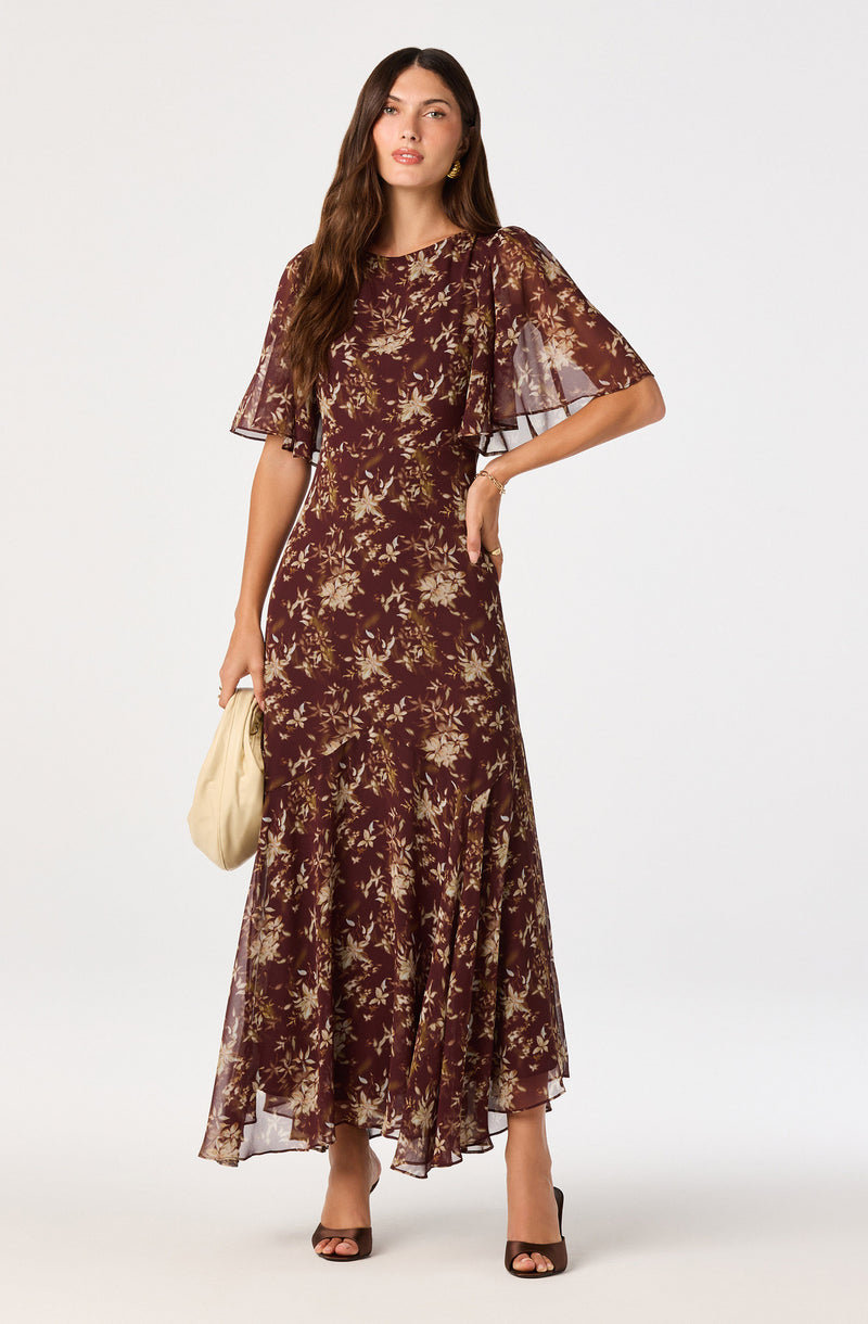 Long floral print dress with sheer bell sleeves, dark background with beige flowers.