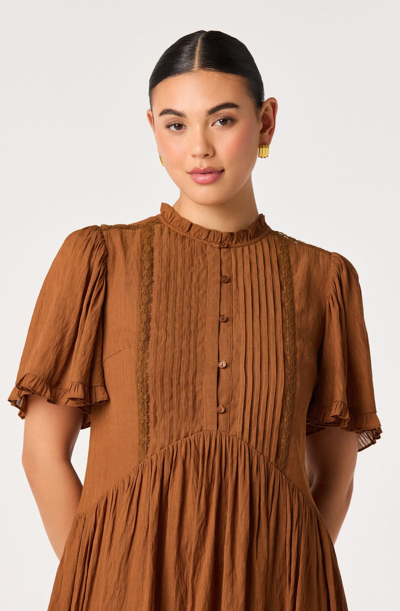 Woman in brown dress with puffed short sleeves, ruffled collar, vertical pleats, and lace details.