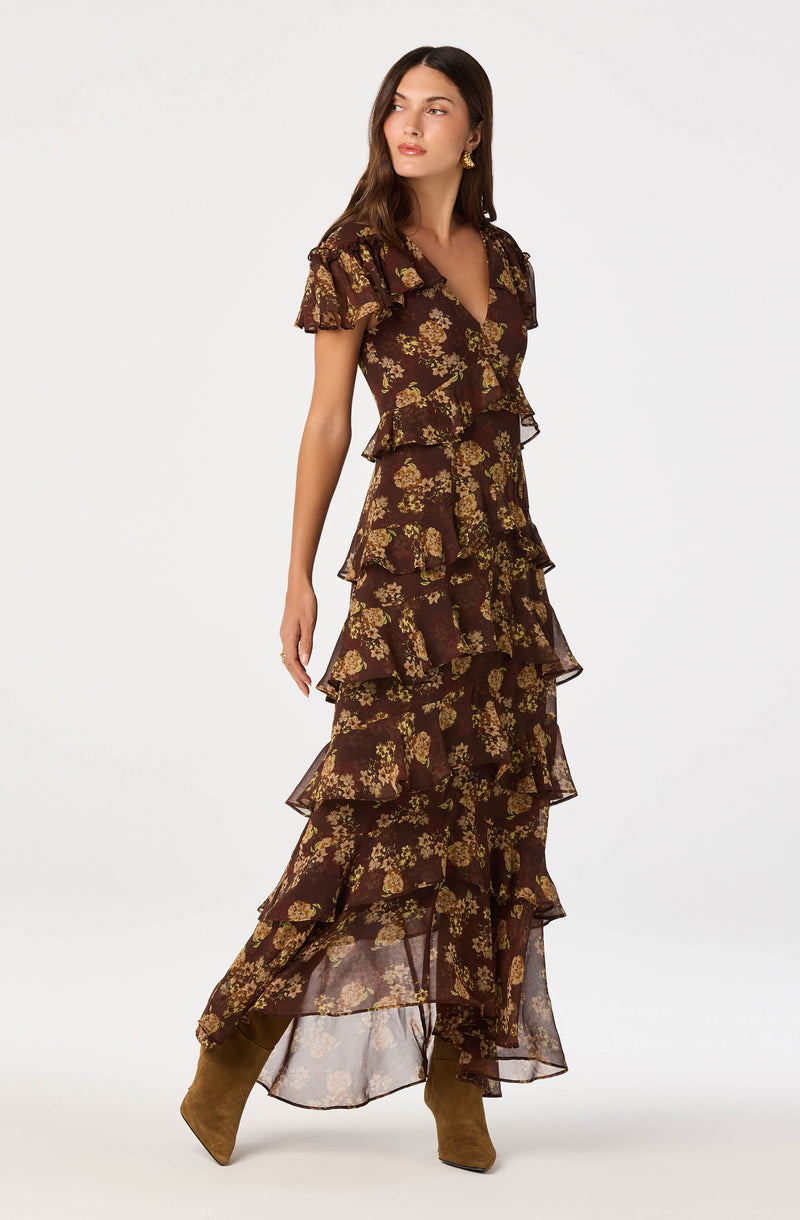 Long brown dress with yellow floral print and ruffled layers.