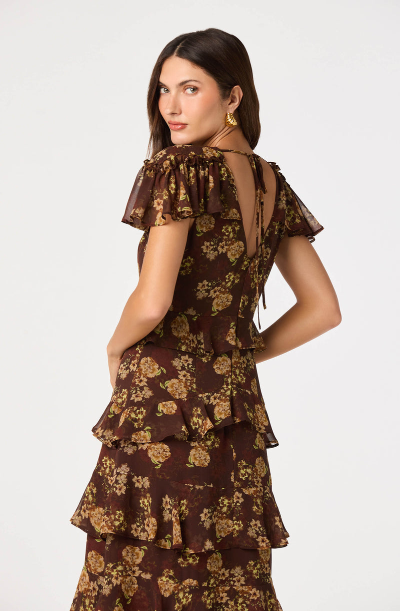 Model wearing a brown floral tiered dress with ruffled sleeves and a keyhole back.