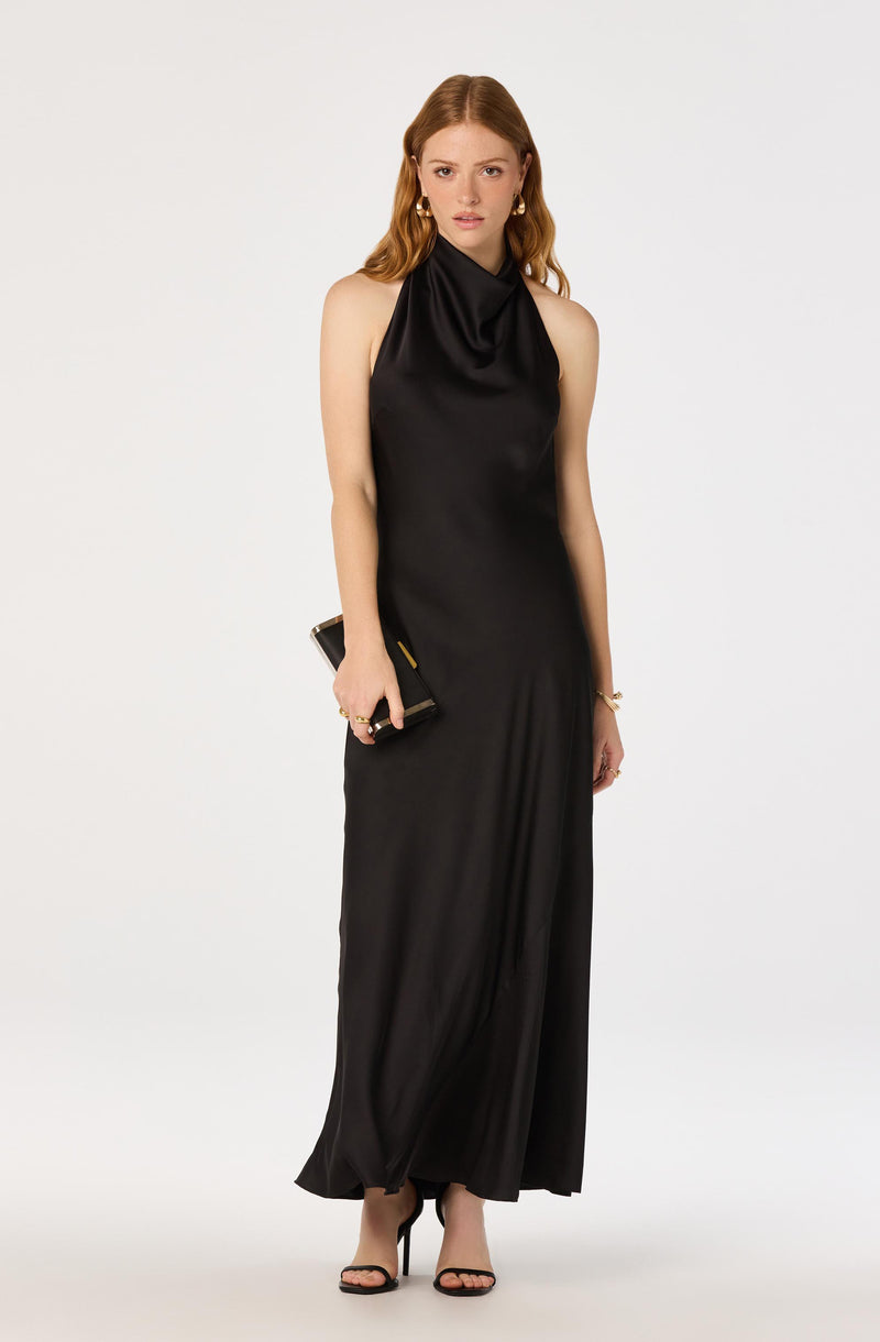 Woman in a long, sleeveless black satin gown with a high neck and draped collar.