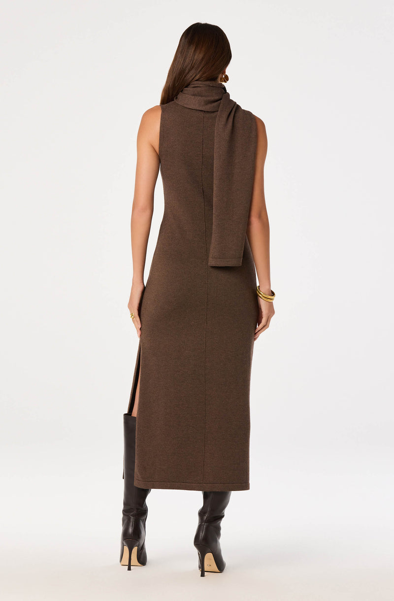 Woman in a sleeveless, brown, long knit dress with a matching scarf, wearing over-the-knee dark brown boots.