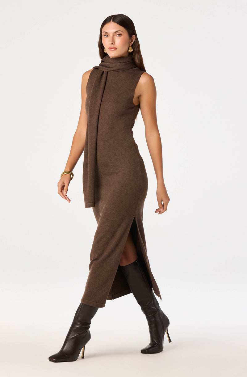 Brown sleeveless knitted dress with a high slit, paired with knee-high black boots.