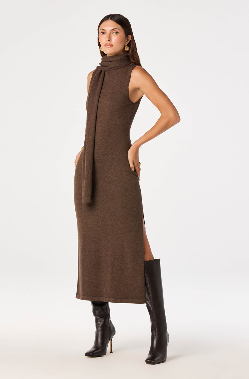 Model wearing a sleeveless, brown knit maxi dress with a turtleneck and matching scarf, paired with black knee-high boots.