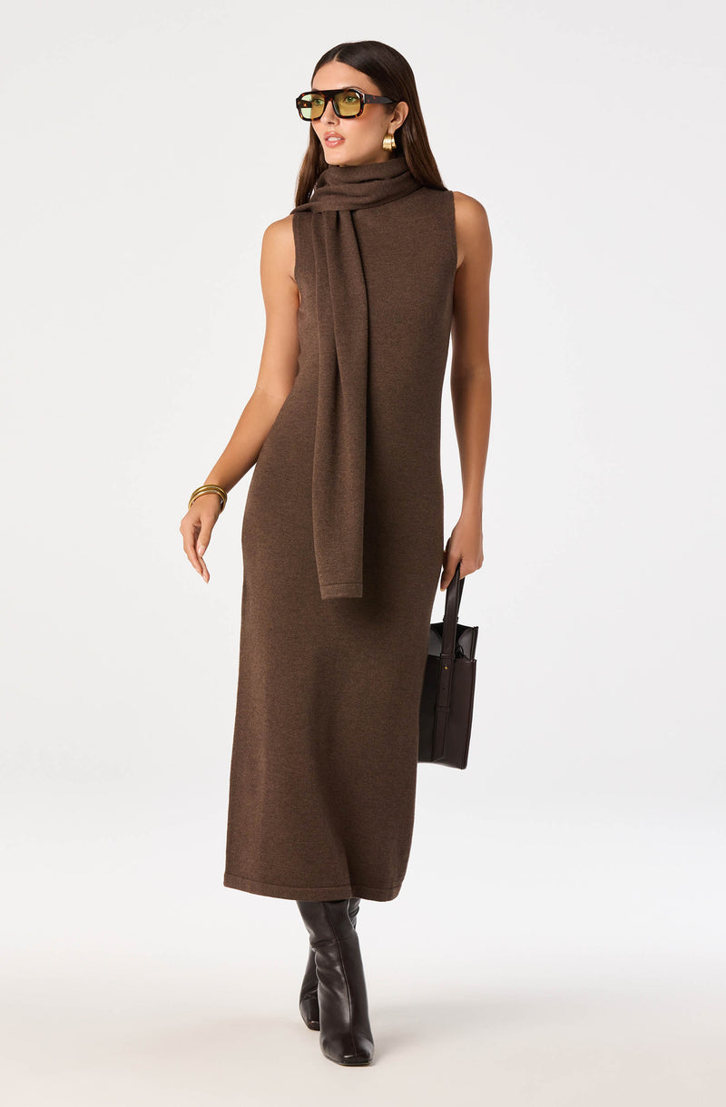 Woman wearing a sleeveless brown knit dress with a matching scarf, black boots, and sunglasses.