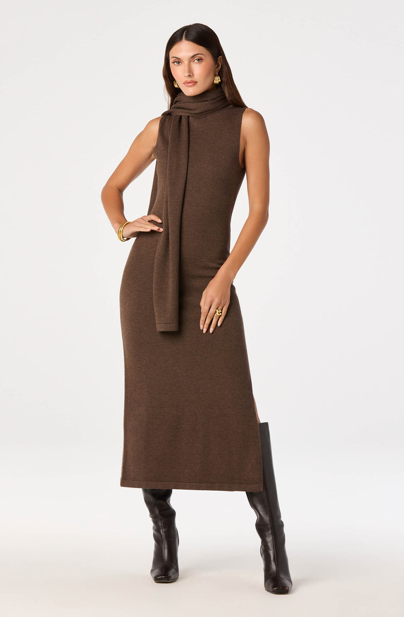 Woman wearing a sleeveless brown dress with a matching scarf, paired with black knee-high boots.
