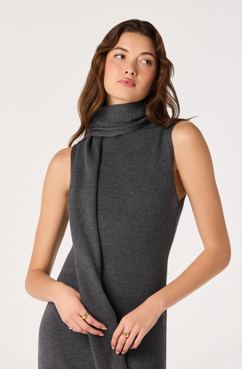 Woman in sleeveless gray dress with a matching gray scarf draped around her neck.