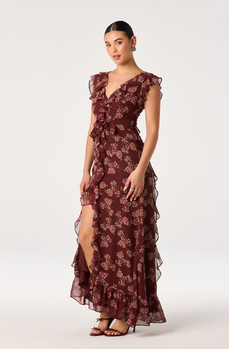 Women in burgundy floral ruffle dress with a front slit, ruffled sleeves, and layered hem.