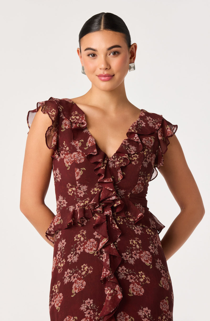 Woman wearing a burgundy floral dress with ruffled sleeves and front ruffle detail.