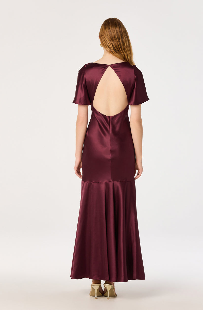 Woman in a burgundy satin gown with a large open back and short sleeves.