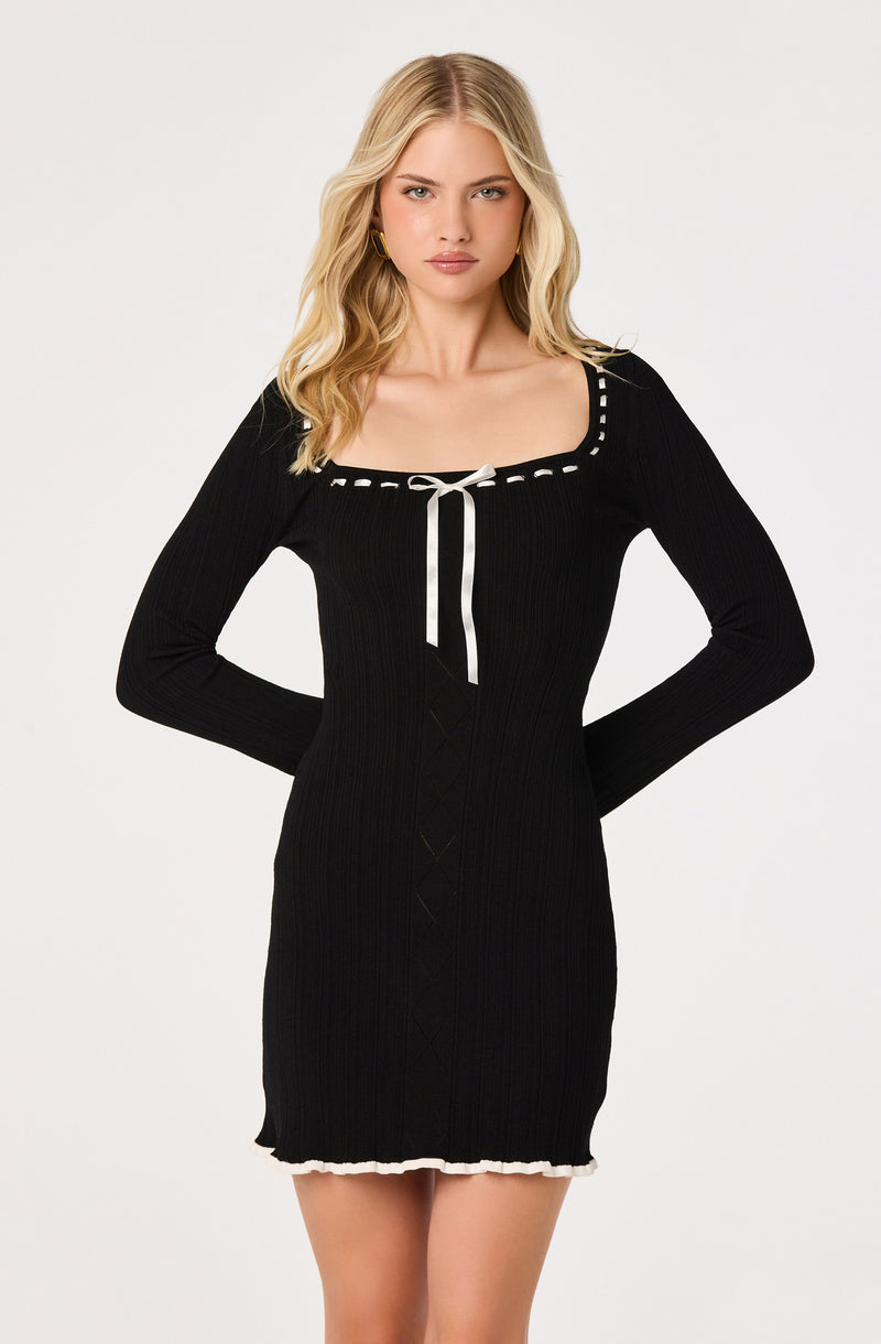 Black ribbed knit dress with white trim, a bow tie at the neckline, and long sleeves.