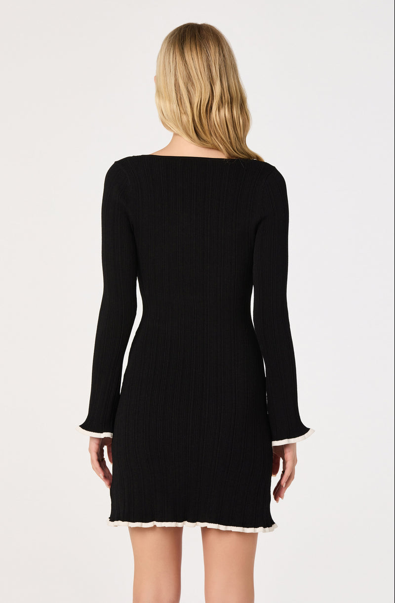 Black ribbed sweater dress with white trim at the cuffs and hem.