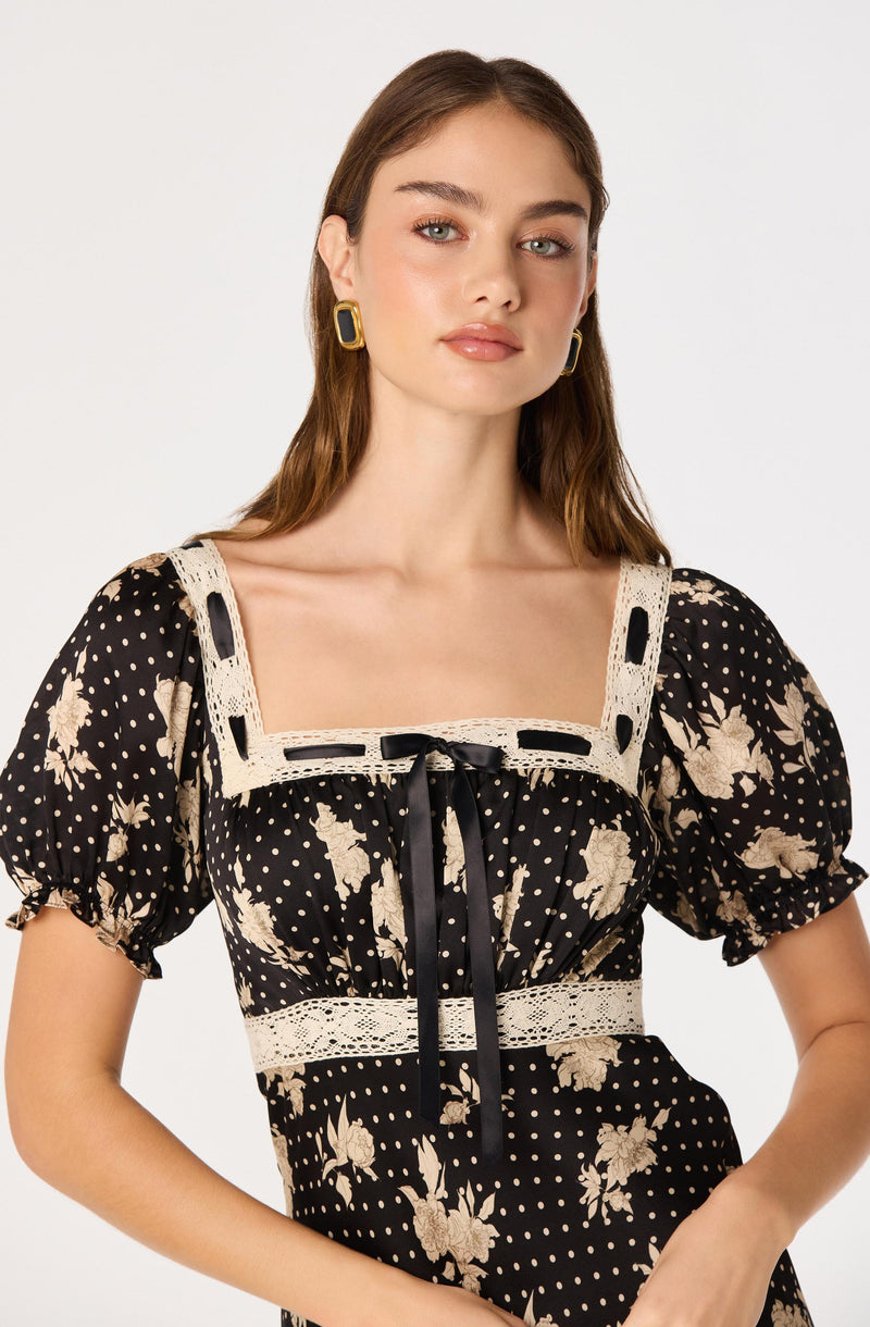 Black dress with beige floral pattern, lace trim, and a black ribbon bow at the neckline.