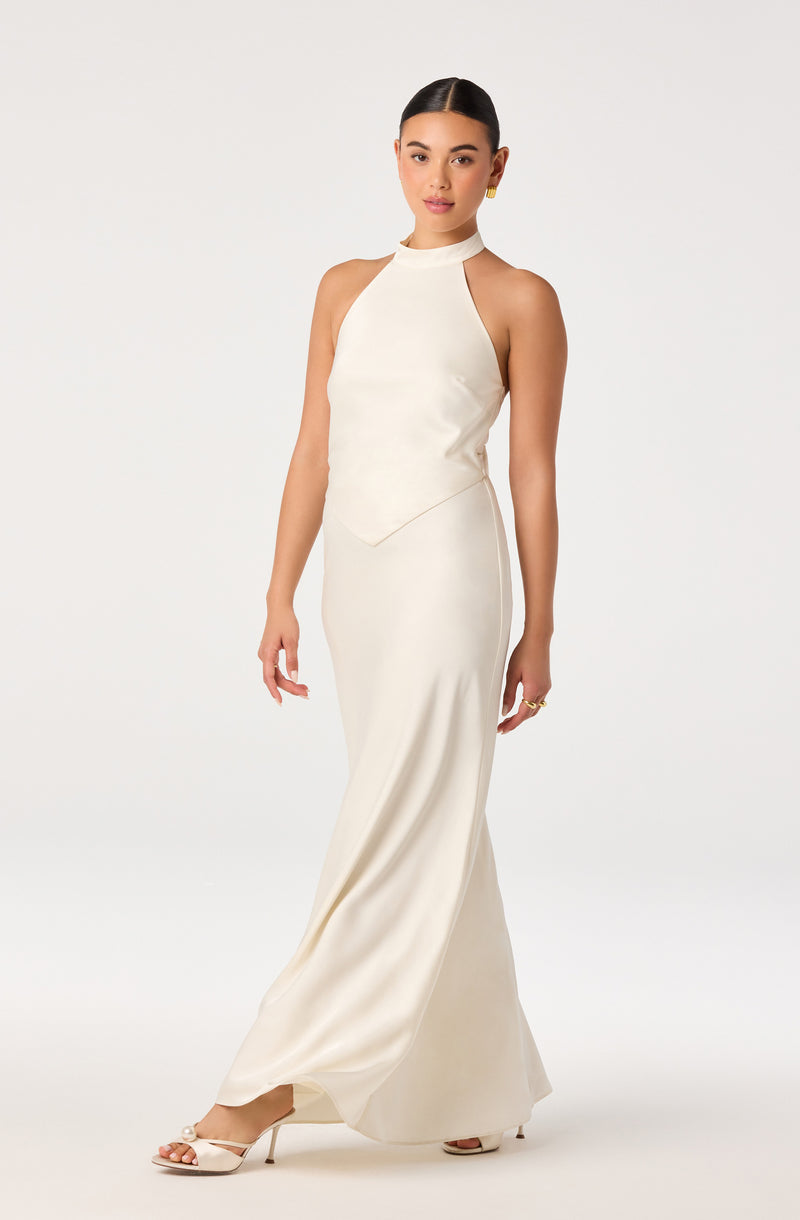 Woman in a long, white satin halter-neck gown with cut-out shoulders and open-toe heels.