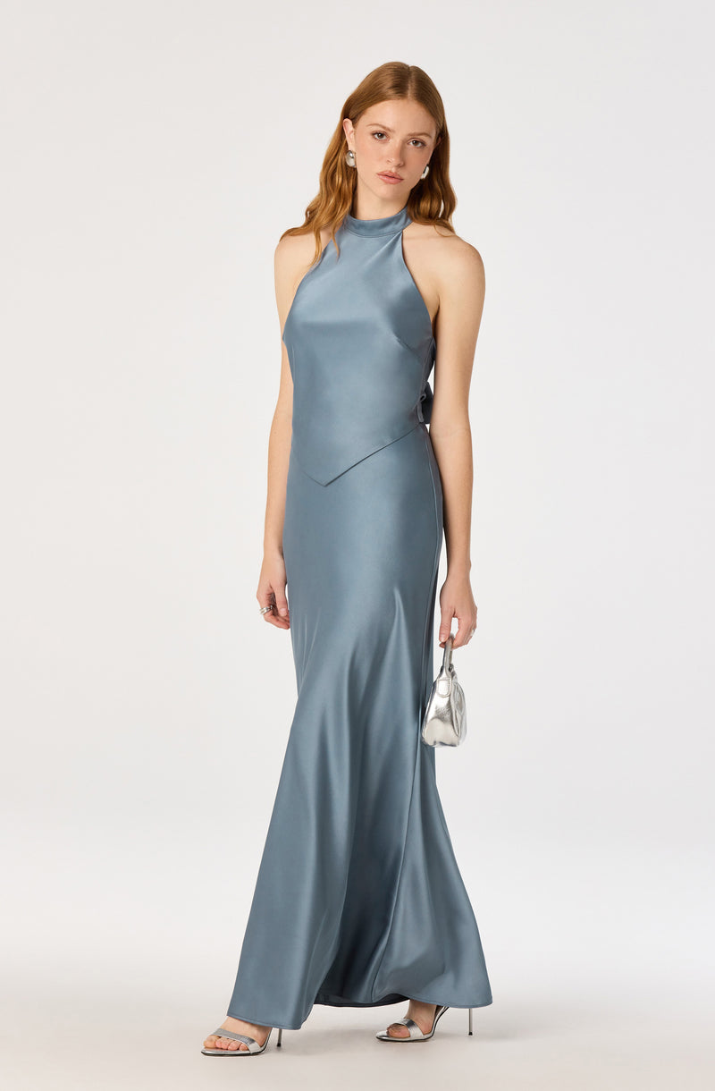 Woman in a silky, sleeveless, high-neck, gray evening gown with a slightly flared hem.