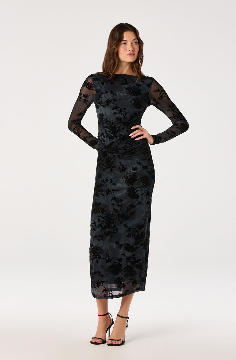 Woman in black floral lace long dress with sheer long sleeves and ankle straps heels.