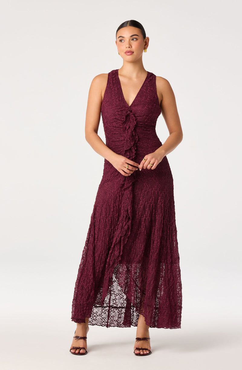 Woman in a sleeveless, deep burgundy lace dress with a ruffled front and high-low hem.
