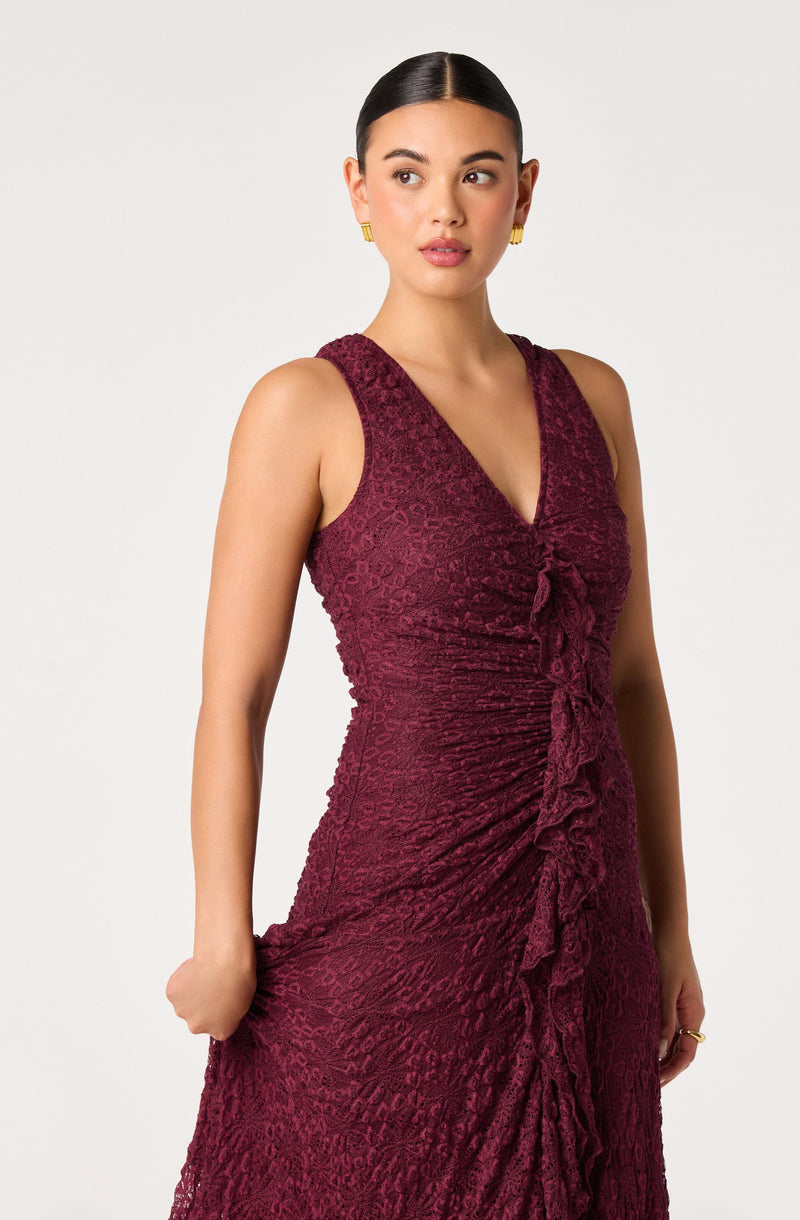 Woman in a sleeveless, deep burgundy lace dress with a ruffled front and fitted silhouette.