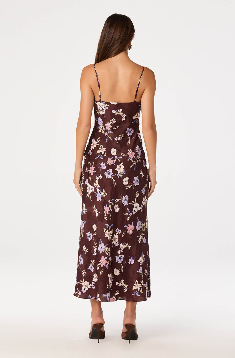 Woman in a dark floral slip dress with thin spaghetti straps, midi length, floral pattern.
