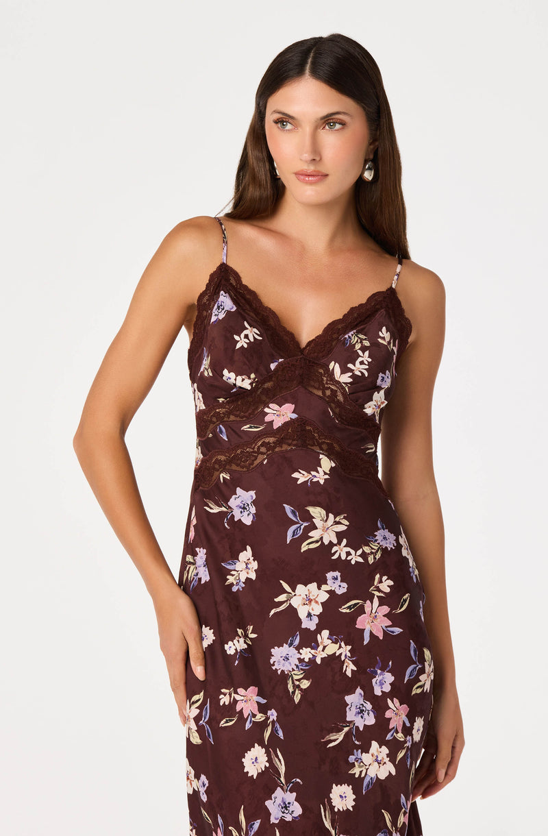 Woman wearing a dark floral slip dress with lace trim and thin straps.