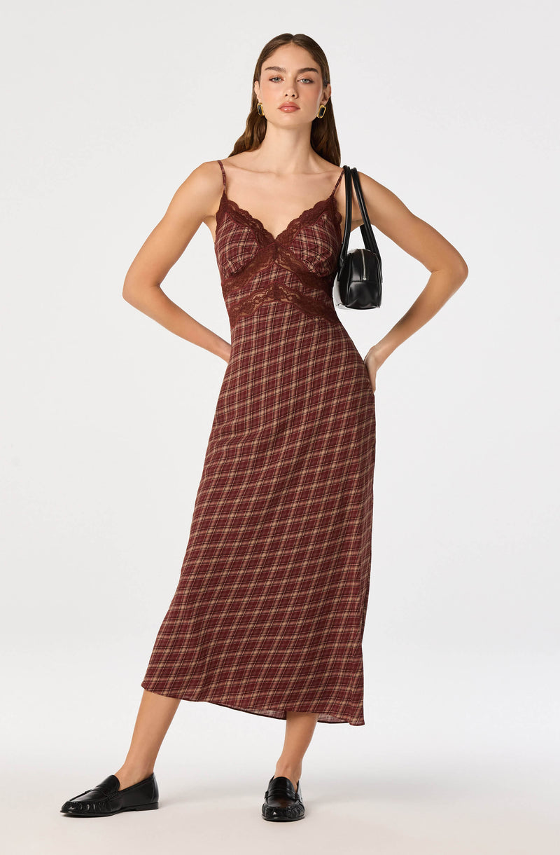 Woman wearing a burgundy plaid and lace slip dress with thin straps, black loafers, and gold hoop earrings.