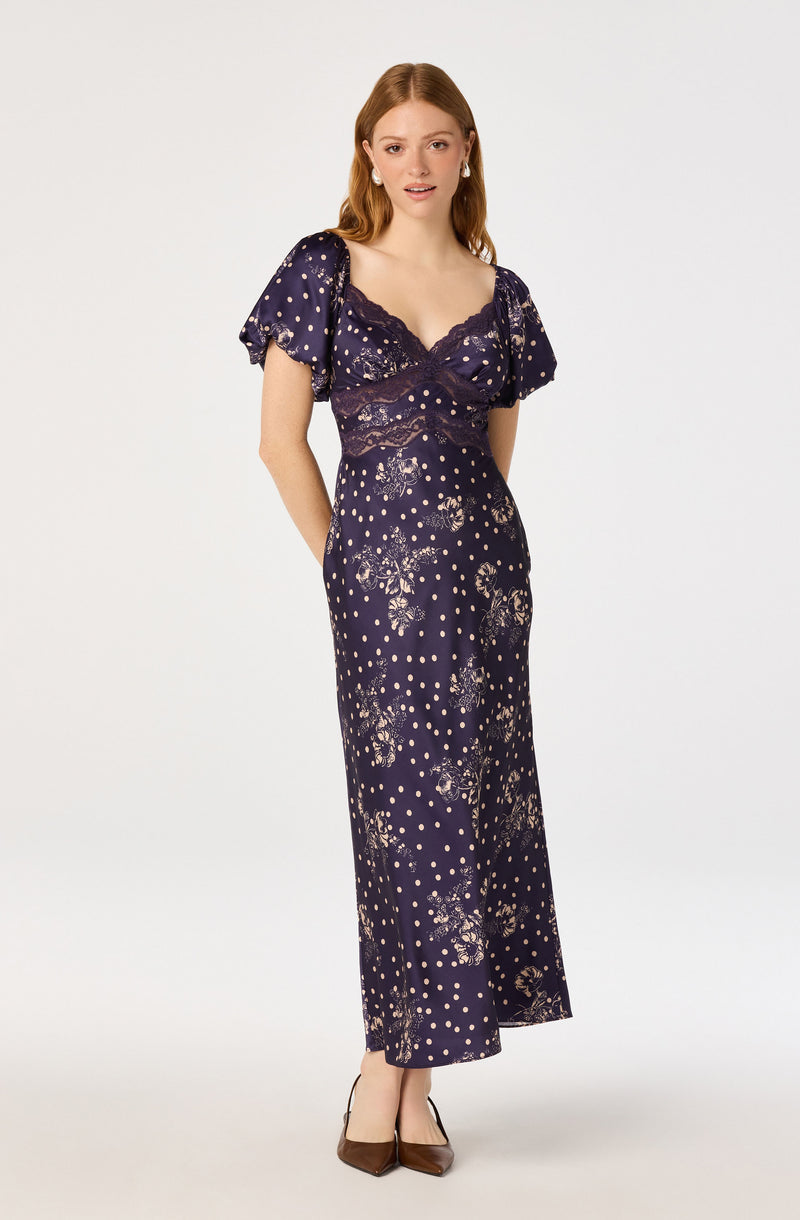 Women in navy floral and polka dot jumpsuit with lace details, short puff sleeves.