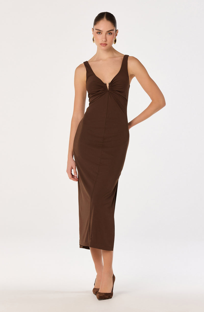 Woman in a brown sleeveless, fitted, ankle-length dress with a ruched front and wide straps.