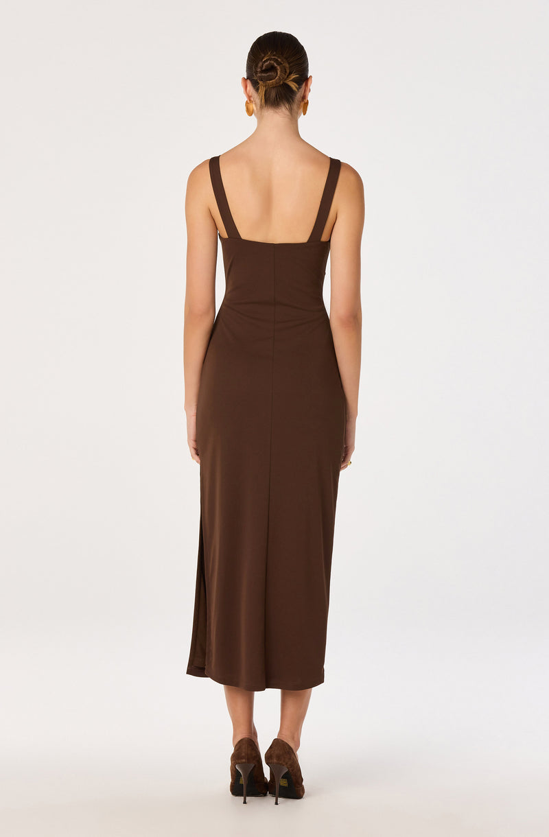 Woman in a sleeveless brown dress with wide shoulder straps, back view.