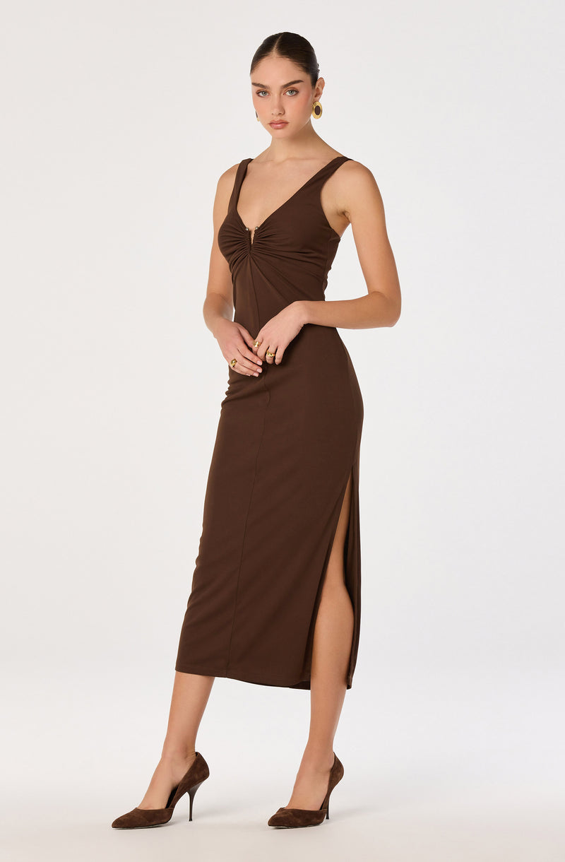 Girl in a brown sleeveless dress with a front zipper and side slit, paired with brown heels.