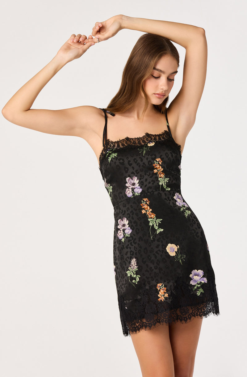 Girl in black floral lace slip dress with spaghetti straps, lace trim at hem.