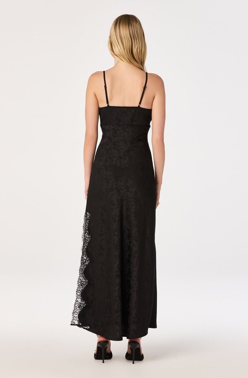 Back view of a woman in a black spaghetti strap jumpsuit with lace detail on the side, wide-leg pants.