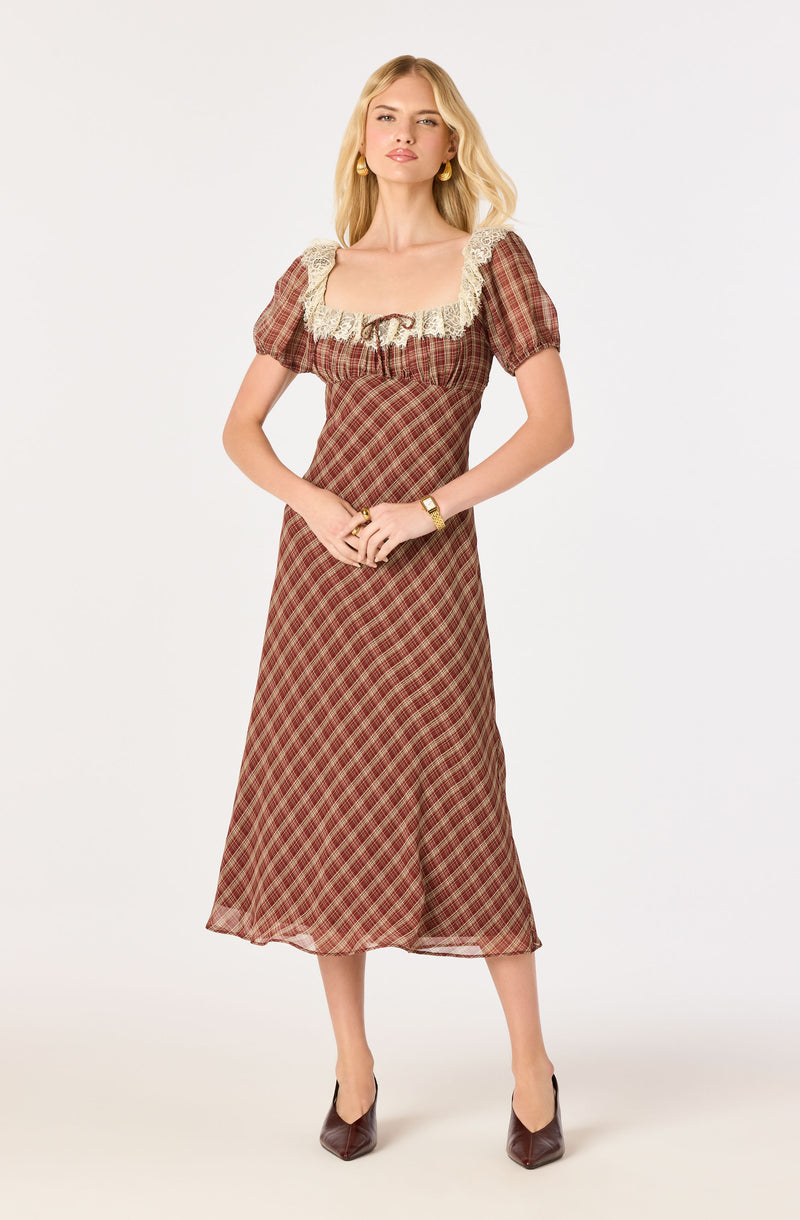 Woman in a long, plaid brown and red dress with puff sleeves and lace trim on the neckline.
