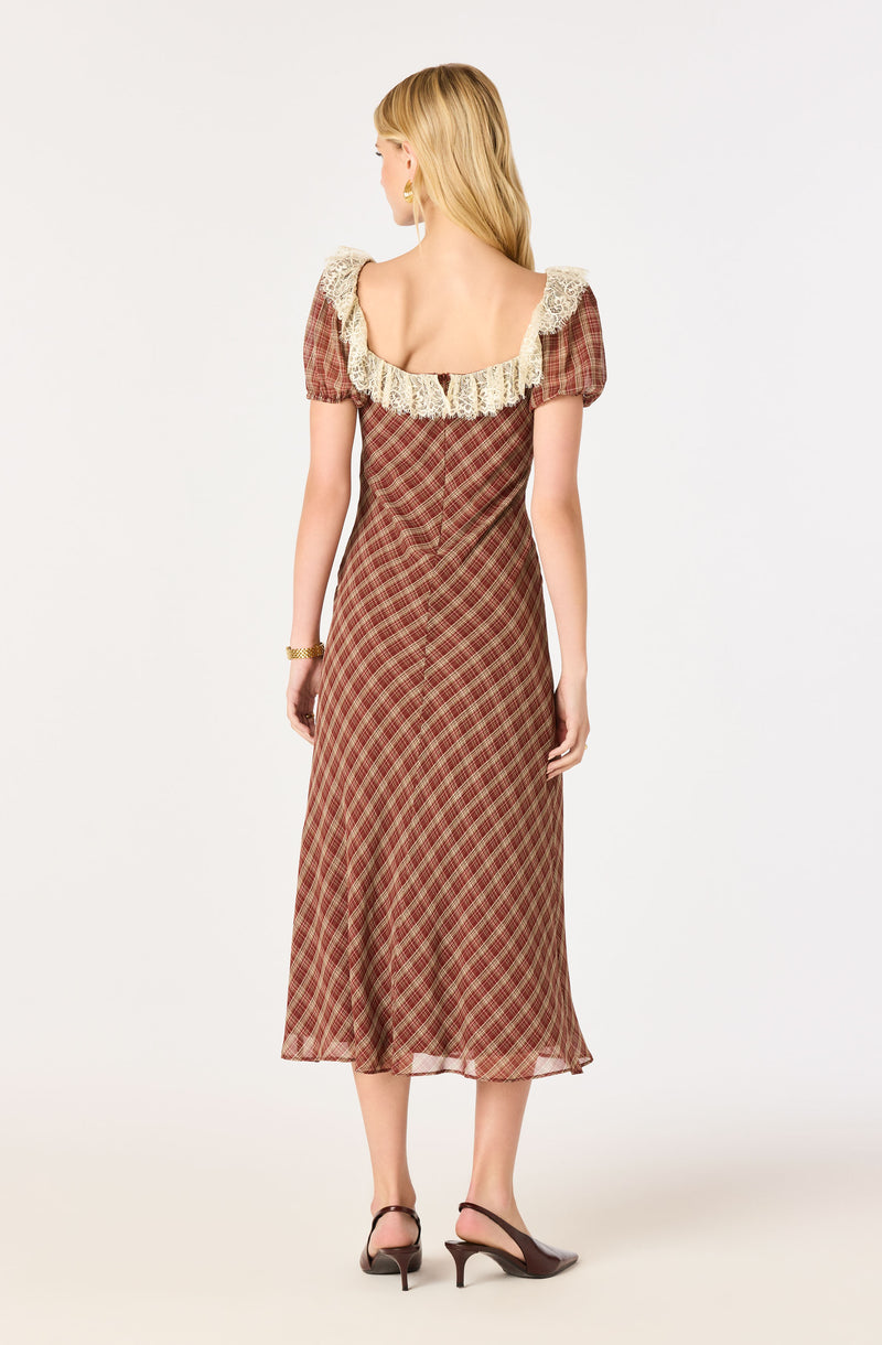 Girl in a plaid midi dress with puff sleeves and lace-trimmed square neckline, wearing black heels.