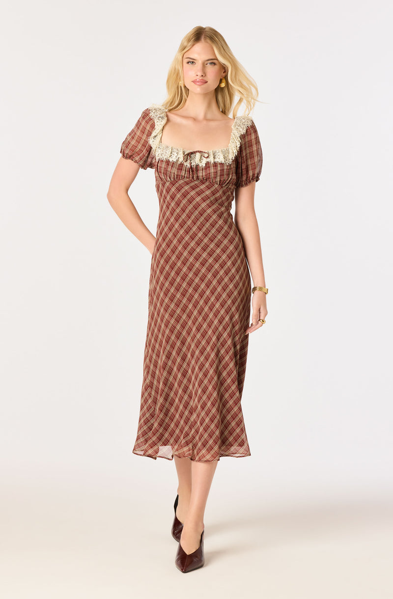 Woman in a plaid brown dress with lace trim, short puff sleeves, and dark heels.