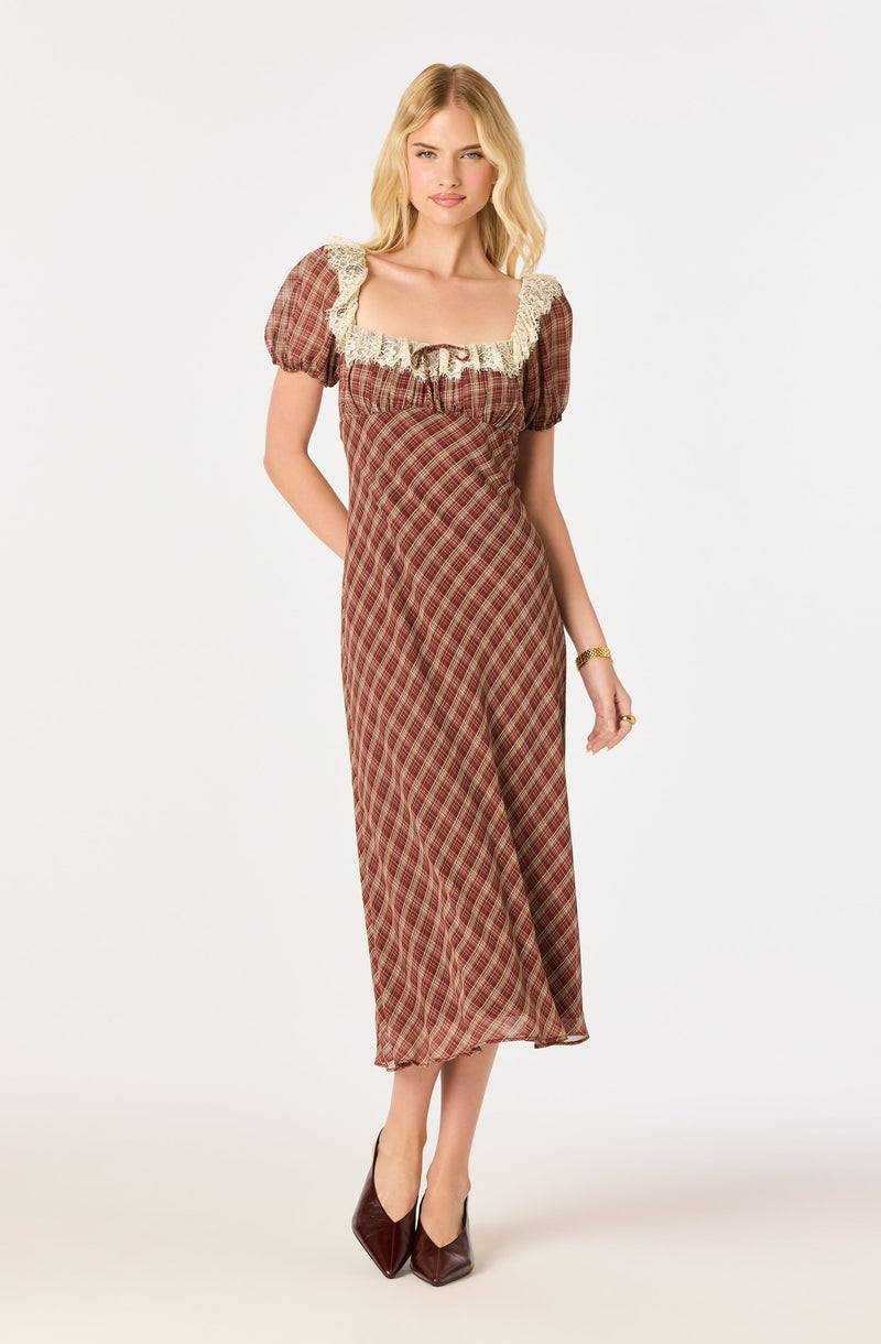 Woman wearing a plaid dress with lace accents on the shoulders and burgundy heels.